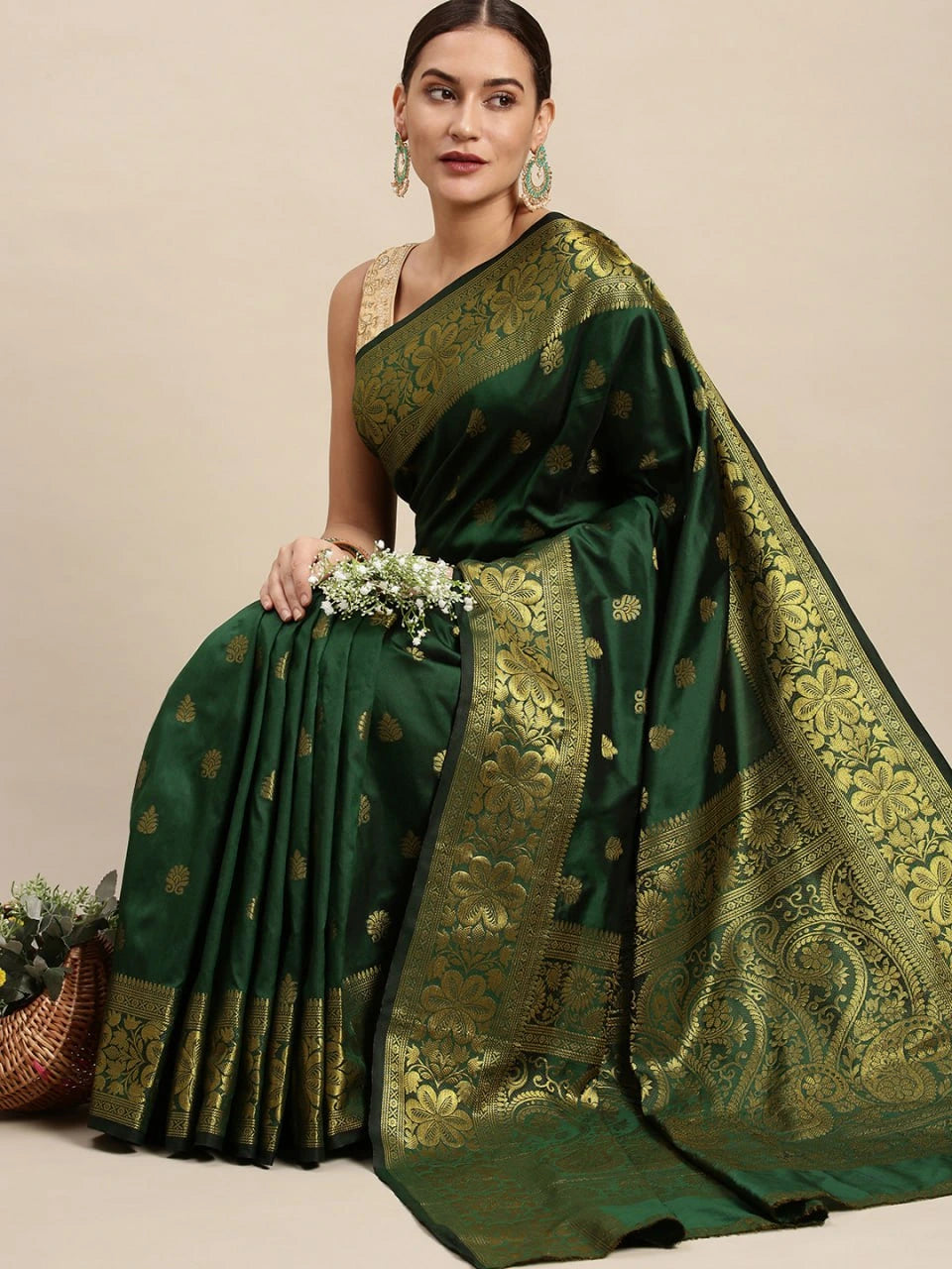 Woman wearing a green saree with gold patterns on a beige background